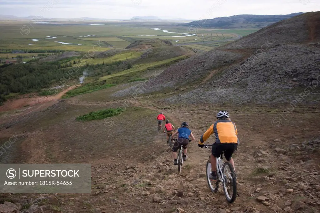 Iceland, Men mountain biking downhill, rear view
