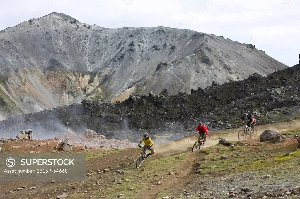 Iceland, Men mountain biking in hilly landscape