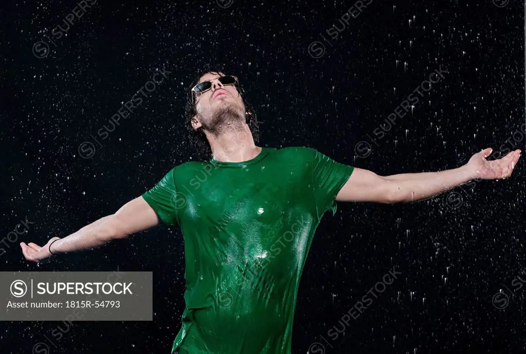 Man standing in rain, stretching arms.