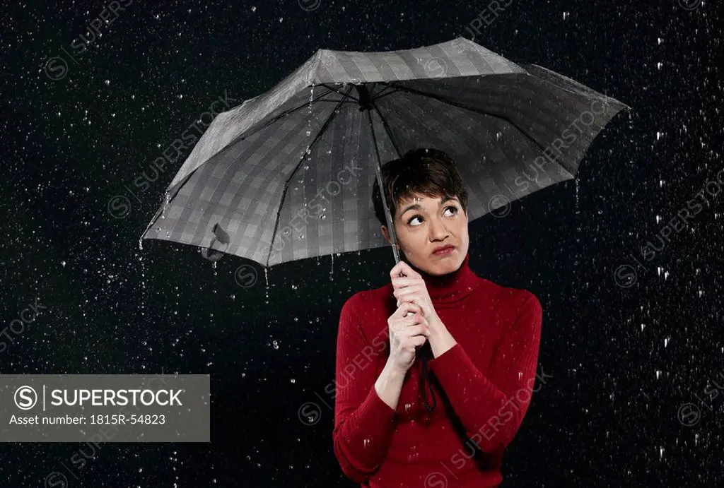 Woman standing in rain, holding umbrella.