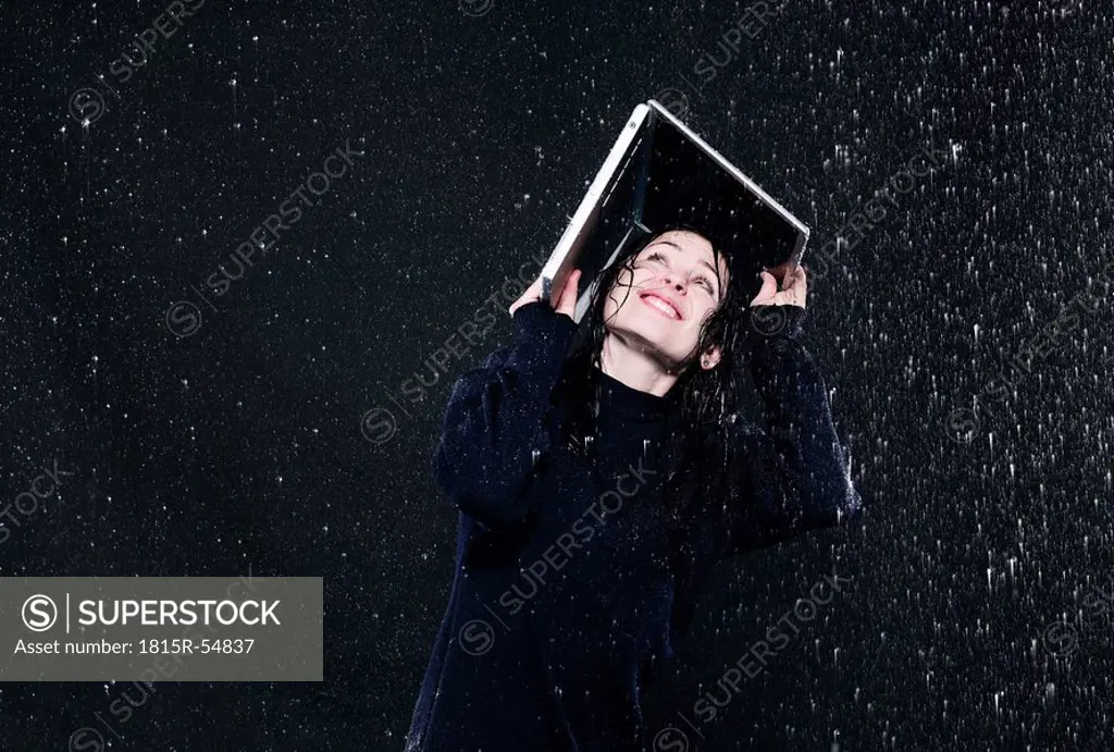 Woman sheltering from rain under laptop.