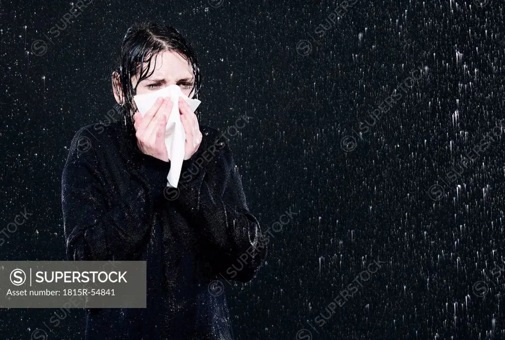 Woman standing in rain, sneezing.