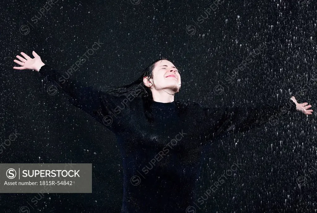 Woman standing in rain, arm outstretched.