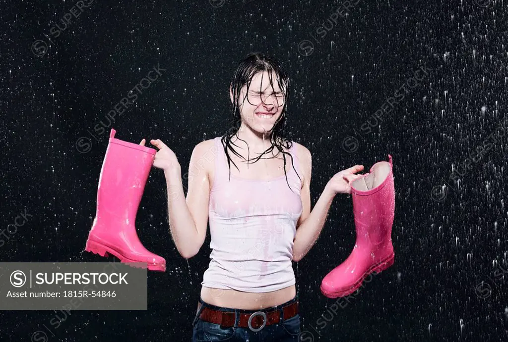 Woman holding rubber boots, clenching teeth.