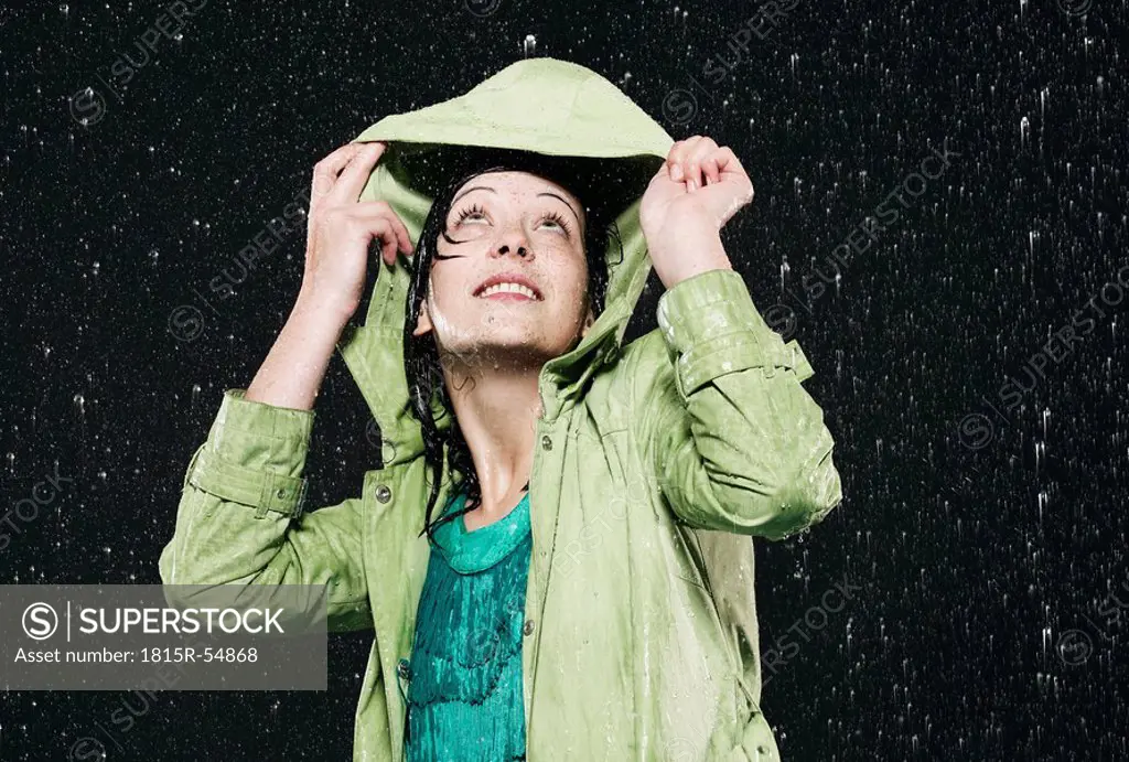 Woman holding hood in rain, looking up