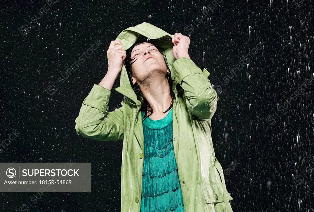 Woman holding hood in rain, looking up.