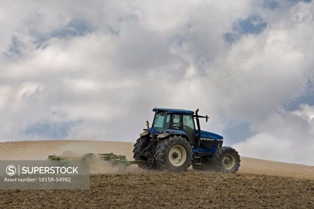 Italy, Tuscany, Tractor driving across field