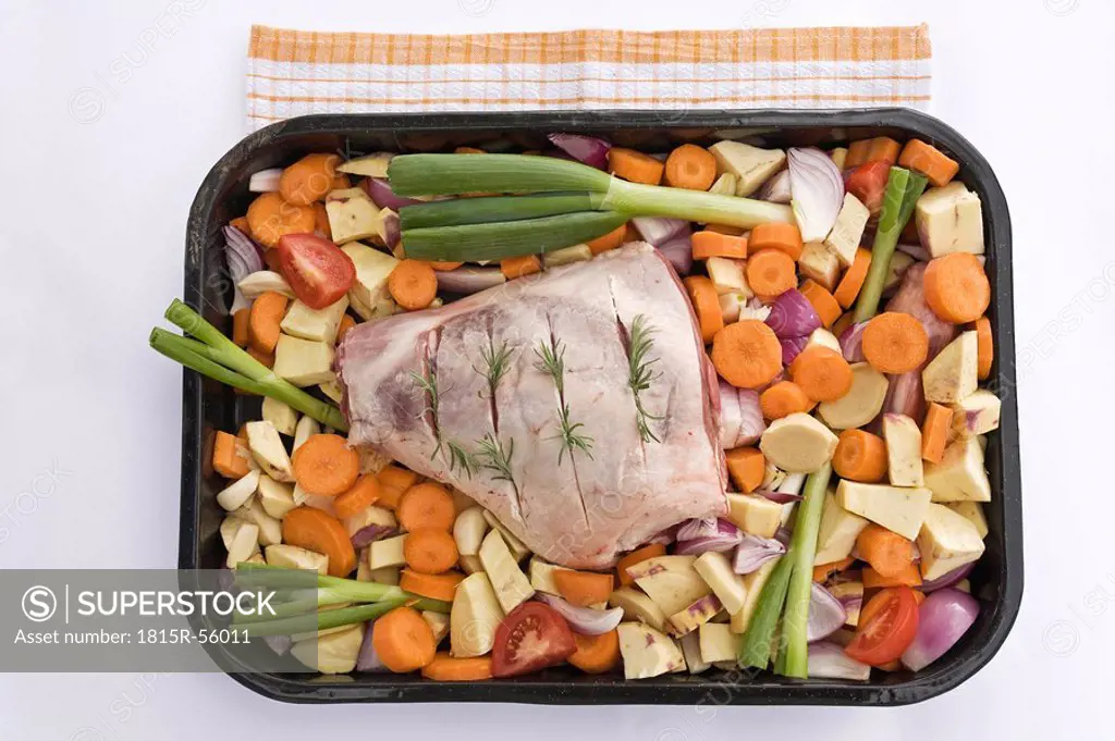 Raw leg of lamb and vegetable in roasting tray, elevated view