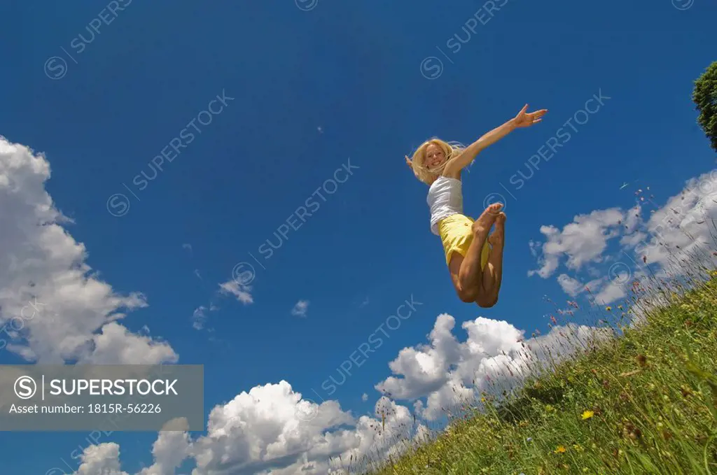 Austria, Salzburger Land, Altenmarkt, Young woman jumping in meadow, smiling
