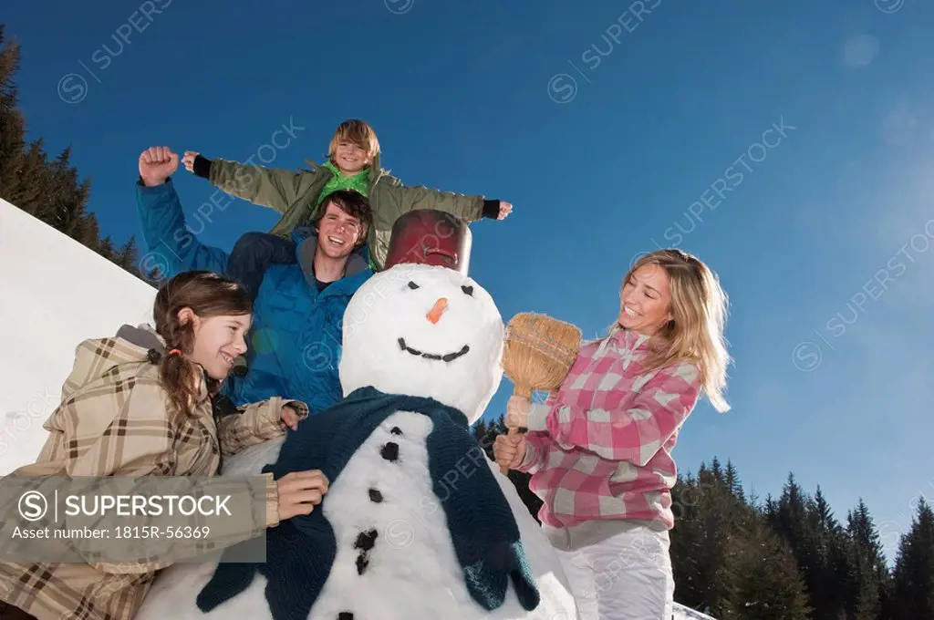 Austria, Salzburger Land, Altenmarkt, Family standing by snowman, smiling, portrait