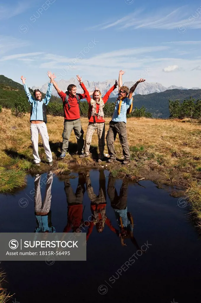 Austria, Salzburger Land, Four hikers by lake cheering