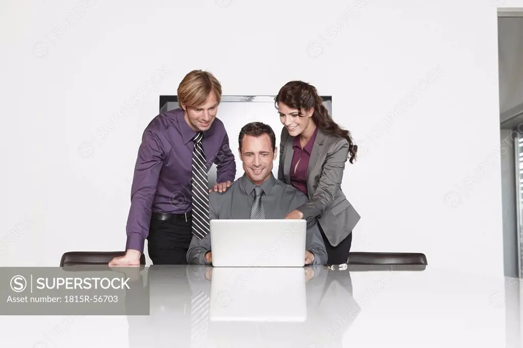 Germany, Cologne, Three business people in office using laptop