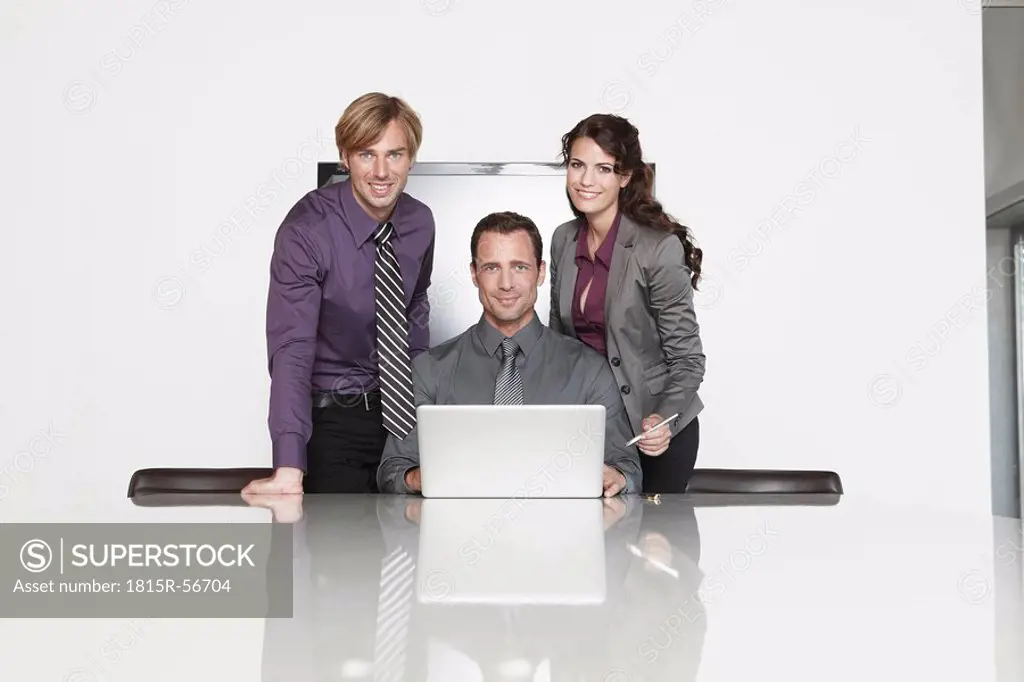 Germany, Cologne, Three Business people in office using laptop