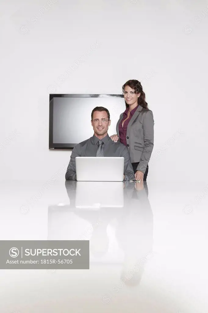 Germany, Cologne, Two business people in conference room using laptop