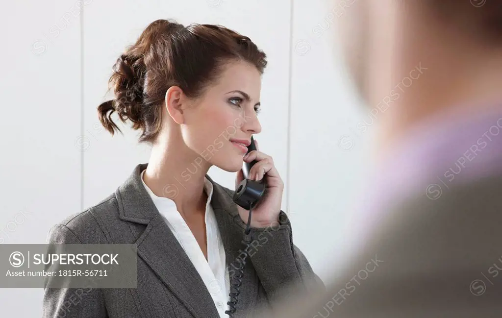 Germany, Cologne, Businesswoman using phone, looking away