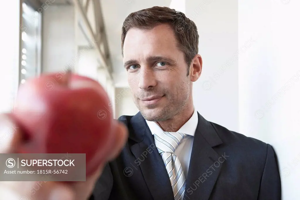 Germany, Cologne, Businessman holding apple, portrait, close_up