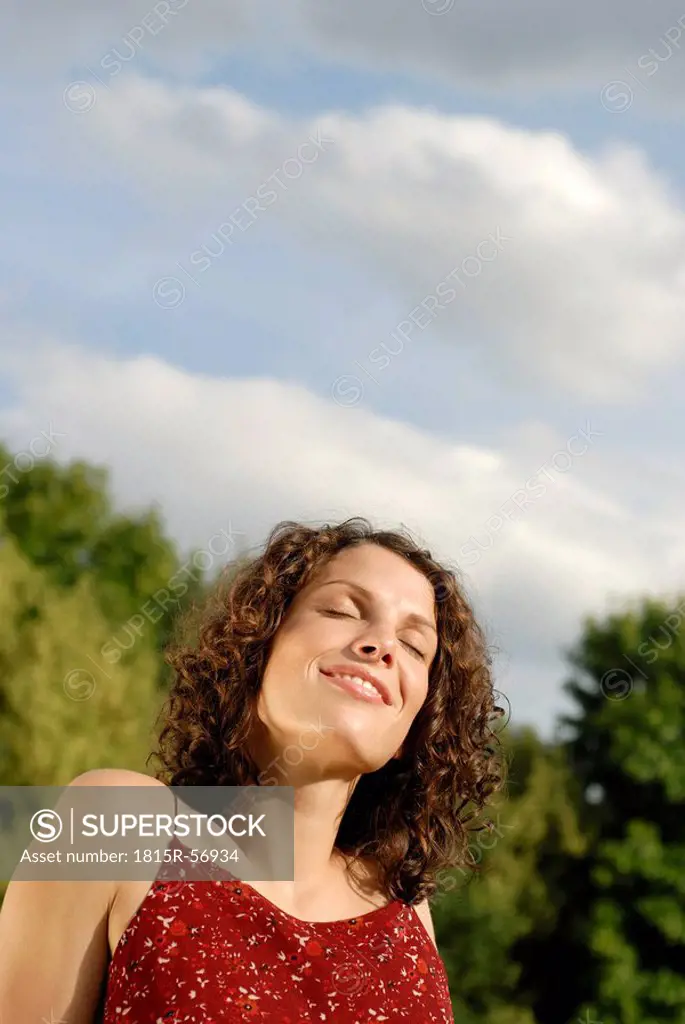 Young woman sunbathing, eyes closed, smiling, portrait
