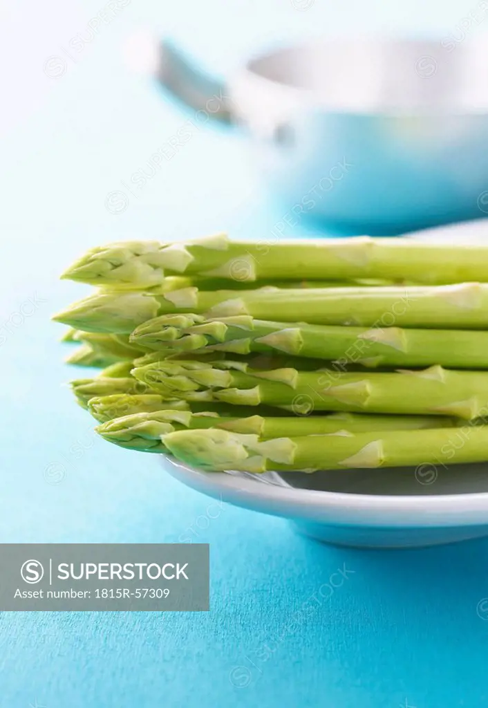 Green asparagus on platter, in background cooking pot