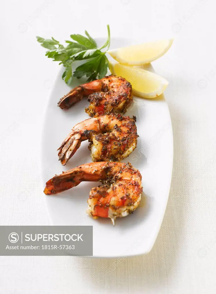 Grilled shrimps, parsley and lemon slices on platter, elevated view