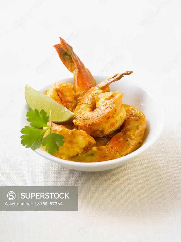 King prawns in curry marinade with lemon slices on plate