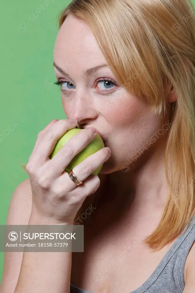 Young woman biting into an apple, portrait