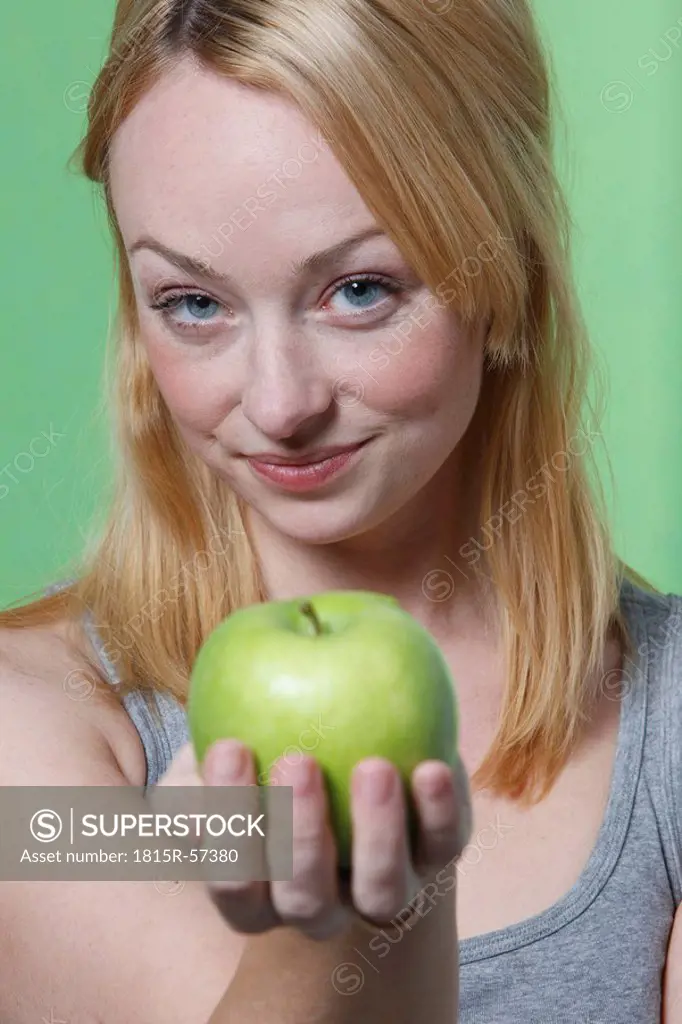 Young woman holding an apple, smiling, portrait