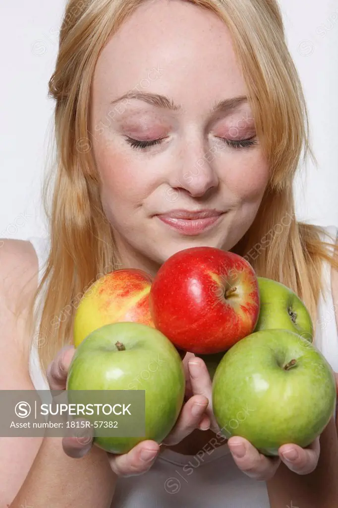Young woman holding apples, eyes closed