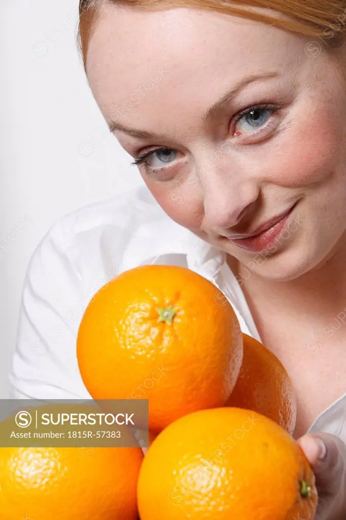 Young woman holding oranges, smiling, portrait