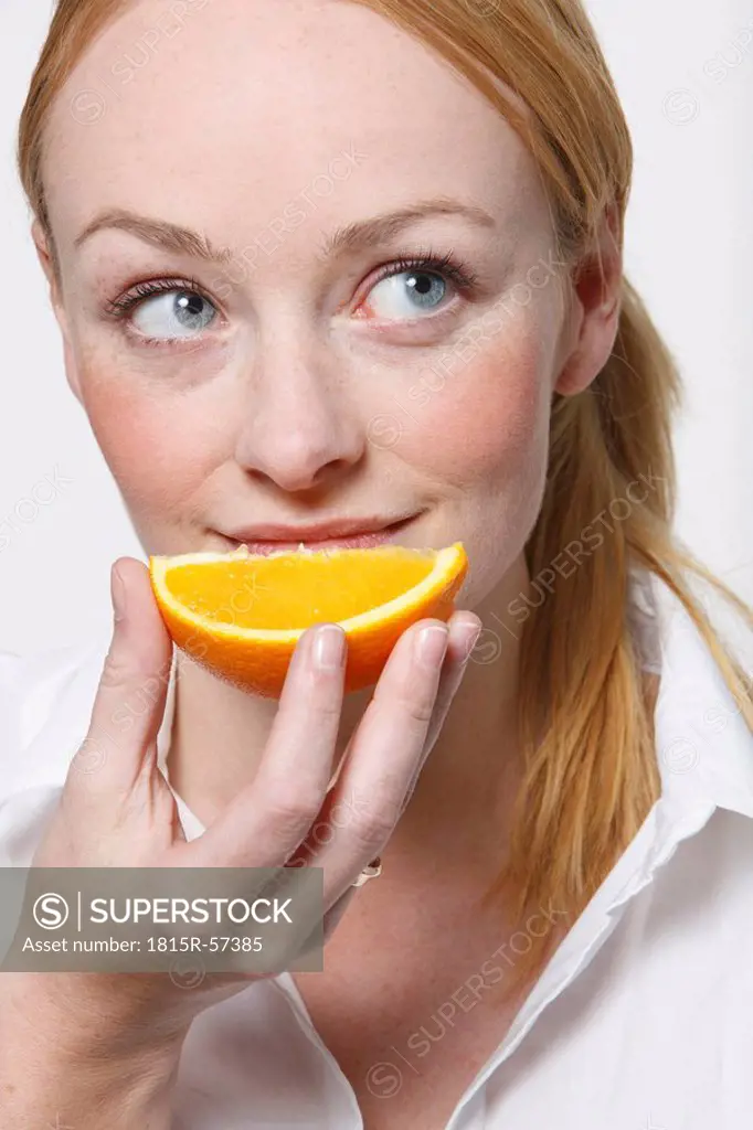 Young woman holding orange slice, portrait