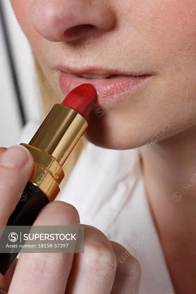 Young woman using lipstick, close up