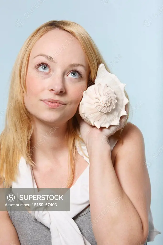 Young woman holding Busycon contrarium snail, portrait