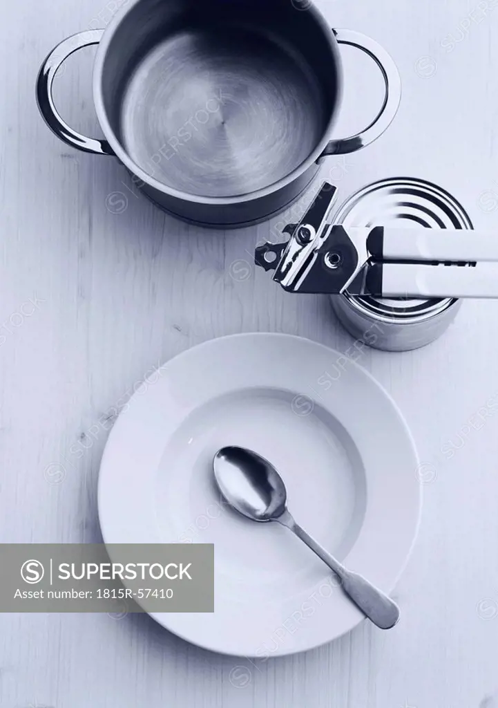 Pot, can and plate with spoon on wooden table, elevated view