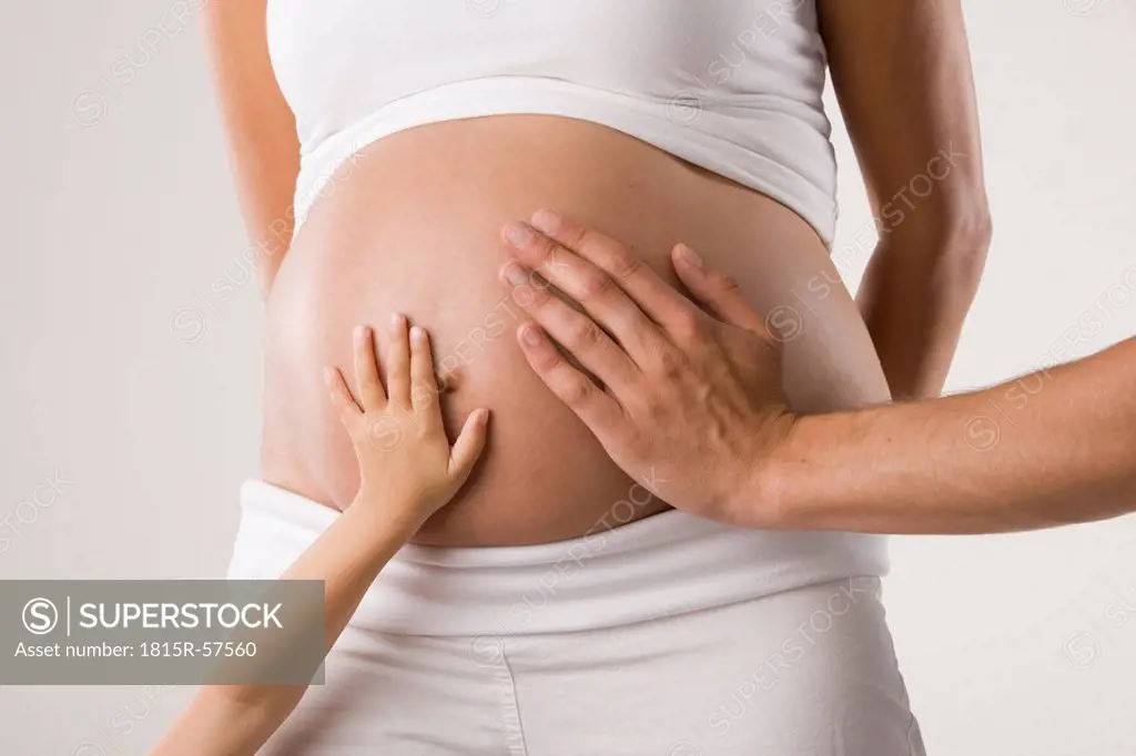 Persons touching woman´s pregnant belly