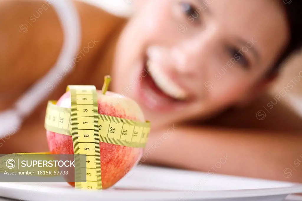Measuring tape wrapped round apple, woman in background