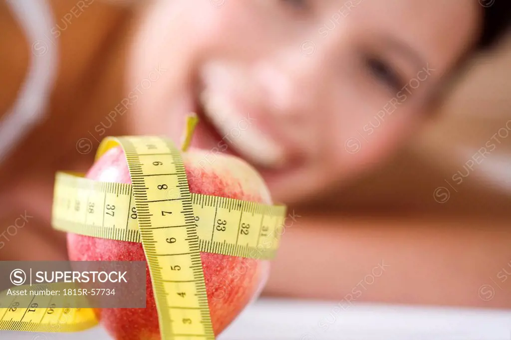 Measuring tape wrapped round apple, woman in background