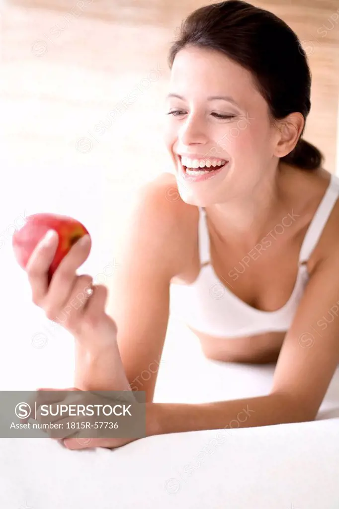 Young woman holding an apple, smiling