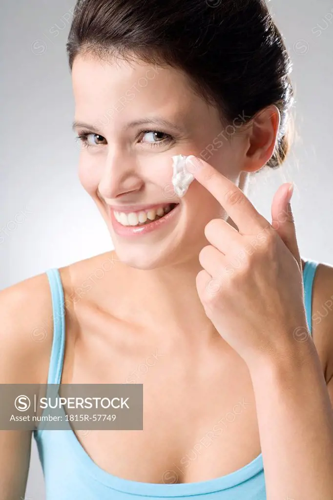 Young woman applying beauty cream, close up