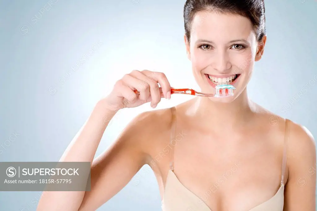 Young woman brushing her teeth, smiling, close up