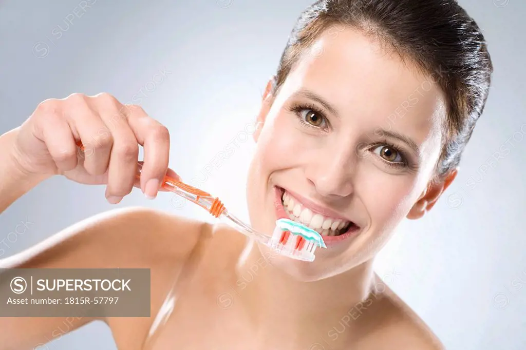 Young woman brushing her teeth, smiling, close up