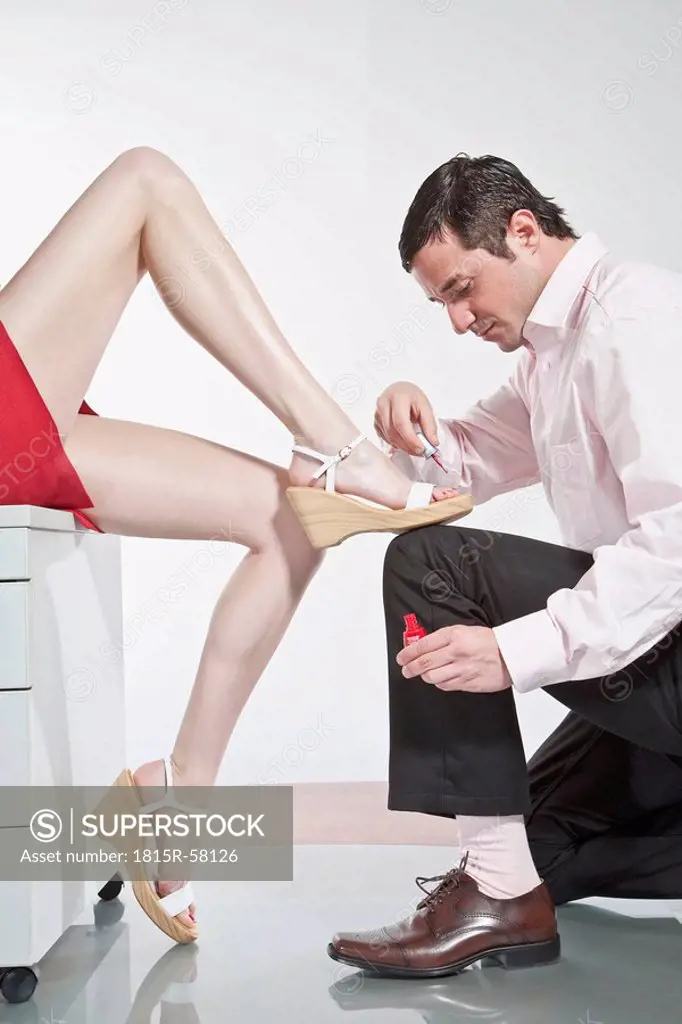 Germany, Business people in office, Man painting woman´s toenails
