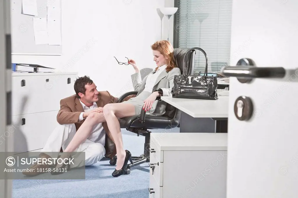 Germany, Business people in office, Business man touching woman´s knee