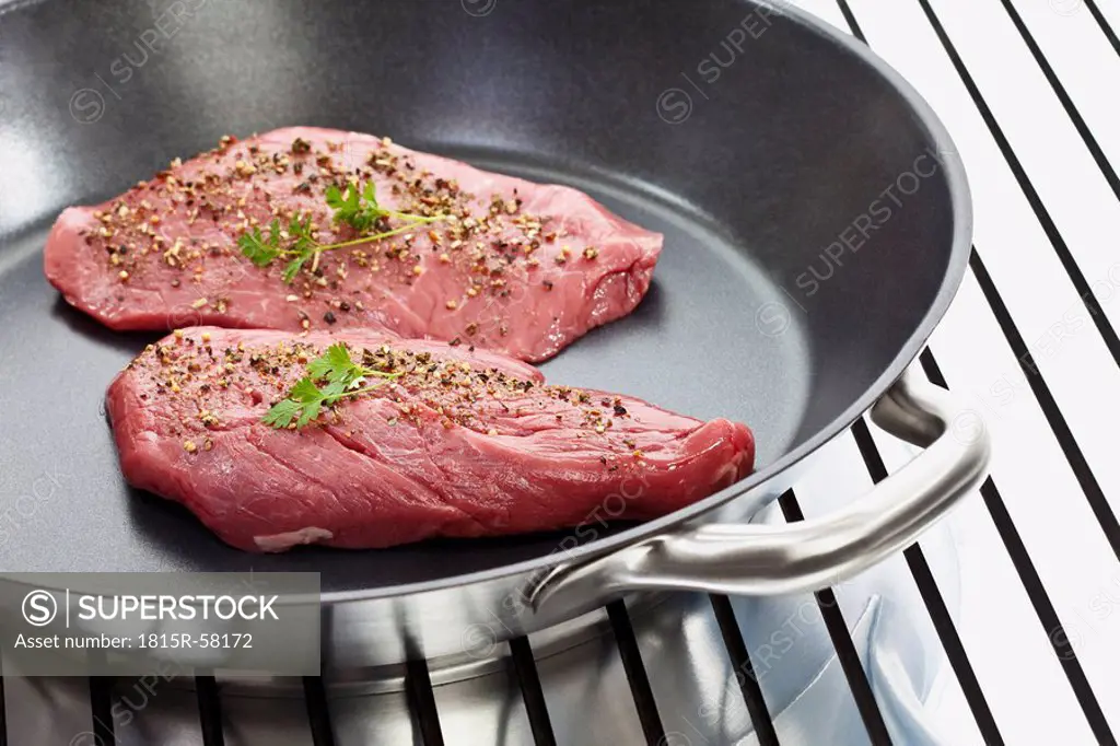 Raw steak in frying pan, close_up