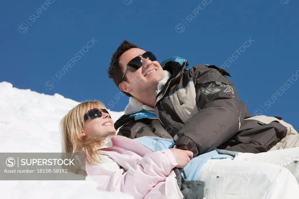 Germany, Bavaria, Couple in winter clothes lying in the snow