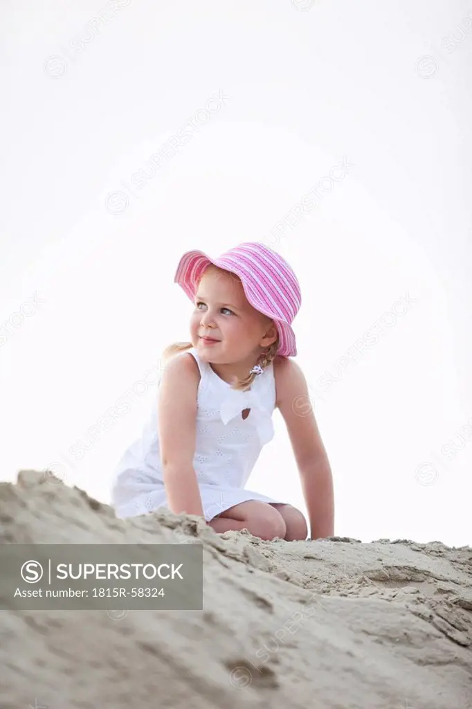 Germany, Girl 4_5 kneeling on sand dune, looking away, portrait