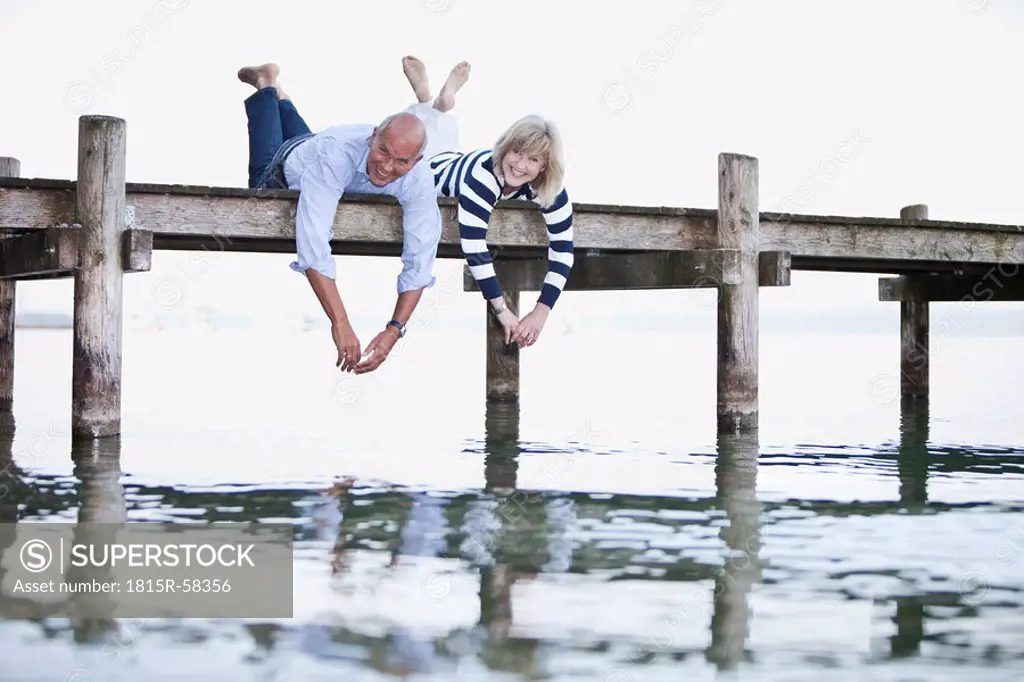 Germany, Bavaria, Starnberger See, Senior couple lying on jetty, smiling, portrait