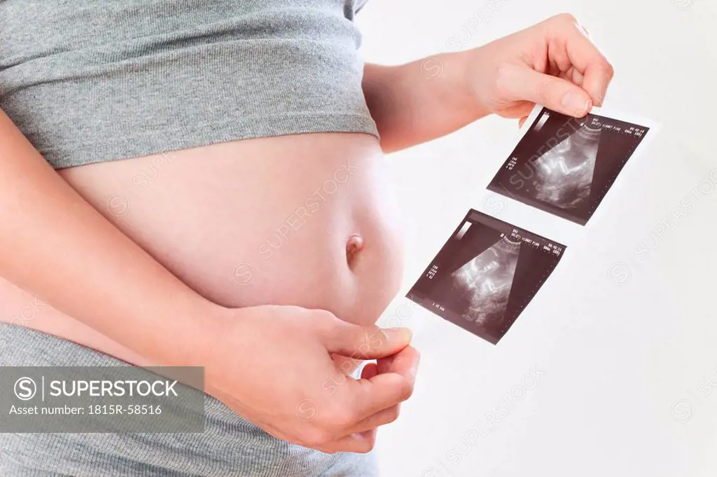Pregnant woman holding ultrasonic pictures, mid_section