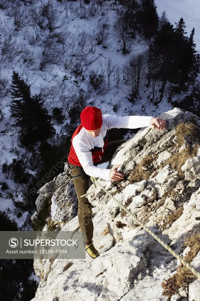 Germany, Bavaria, young woman climbing on rock