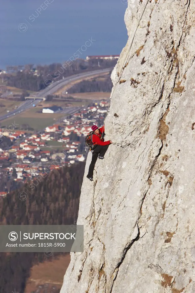 Germany, Bavaria, man climbing on rock face, side view