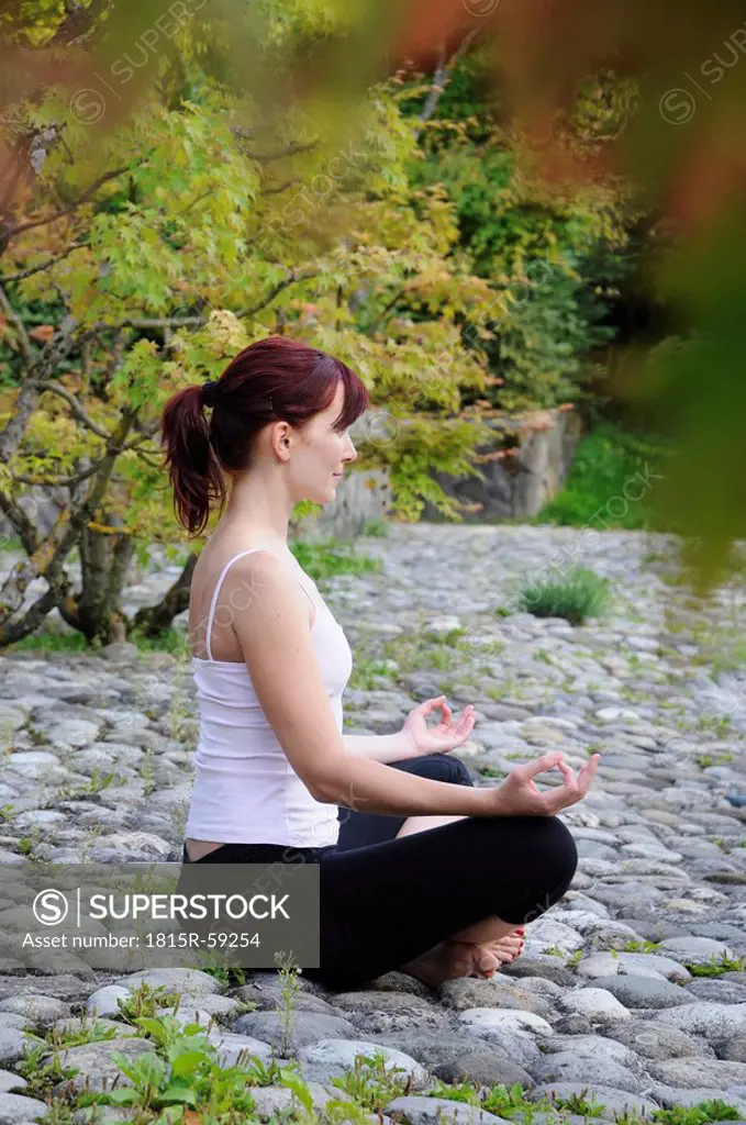 Germany, Bavaria, Munich, Young woman exercising yoga