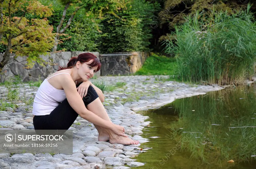 Germany, Bavaria, Munich, Young woman relaxing on lakeshore